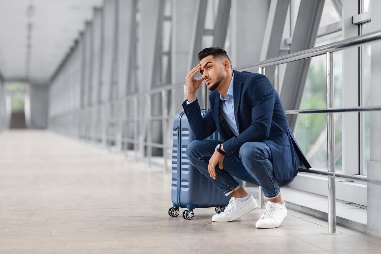 Missed Flight. Upset Middle Eastern Man Sitting Next To Suitcase At Airport